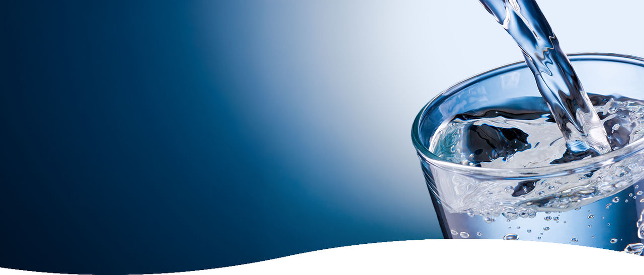 bicchiere riempito con acqua che cade dall'alto